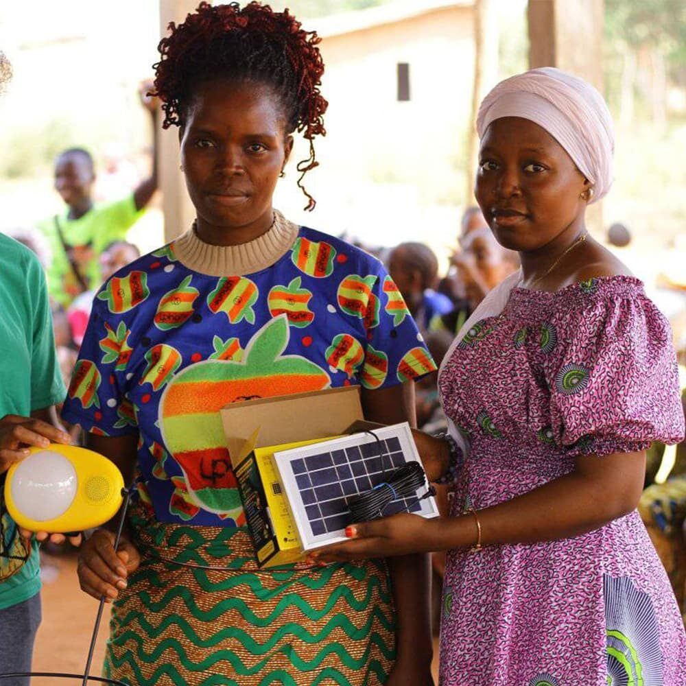 connecting-resources-movements-solar Two women with solar-powered devices in rural setting.